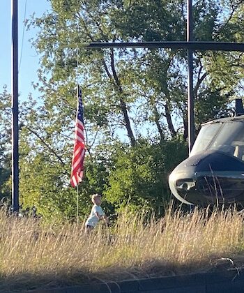 little boy looking up at American flag and military helicopter