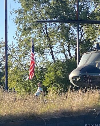 little boy looking up at American flag and military helicopter