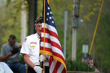 Old Veteran in uniform carrying a flag